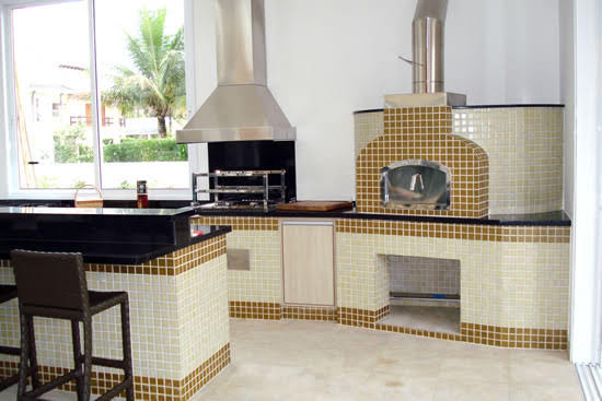 Ambiente completo, com churrasqueira, coifa, forno a lenha e elétrico, balcão e refrigeradores