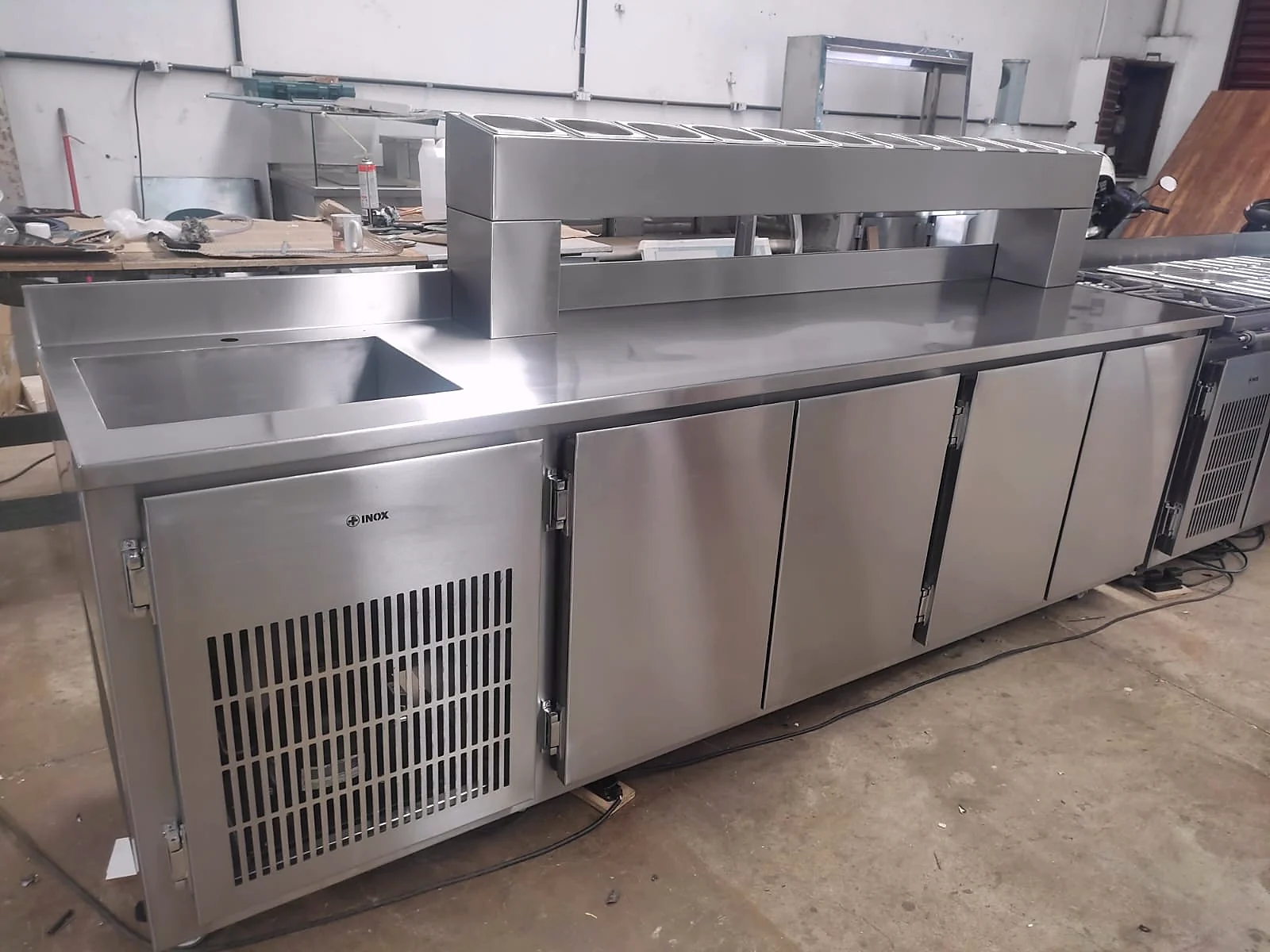 Balcão refrigerado em inox com cuba embutida, prateleira aérea e portas na base