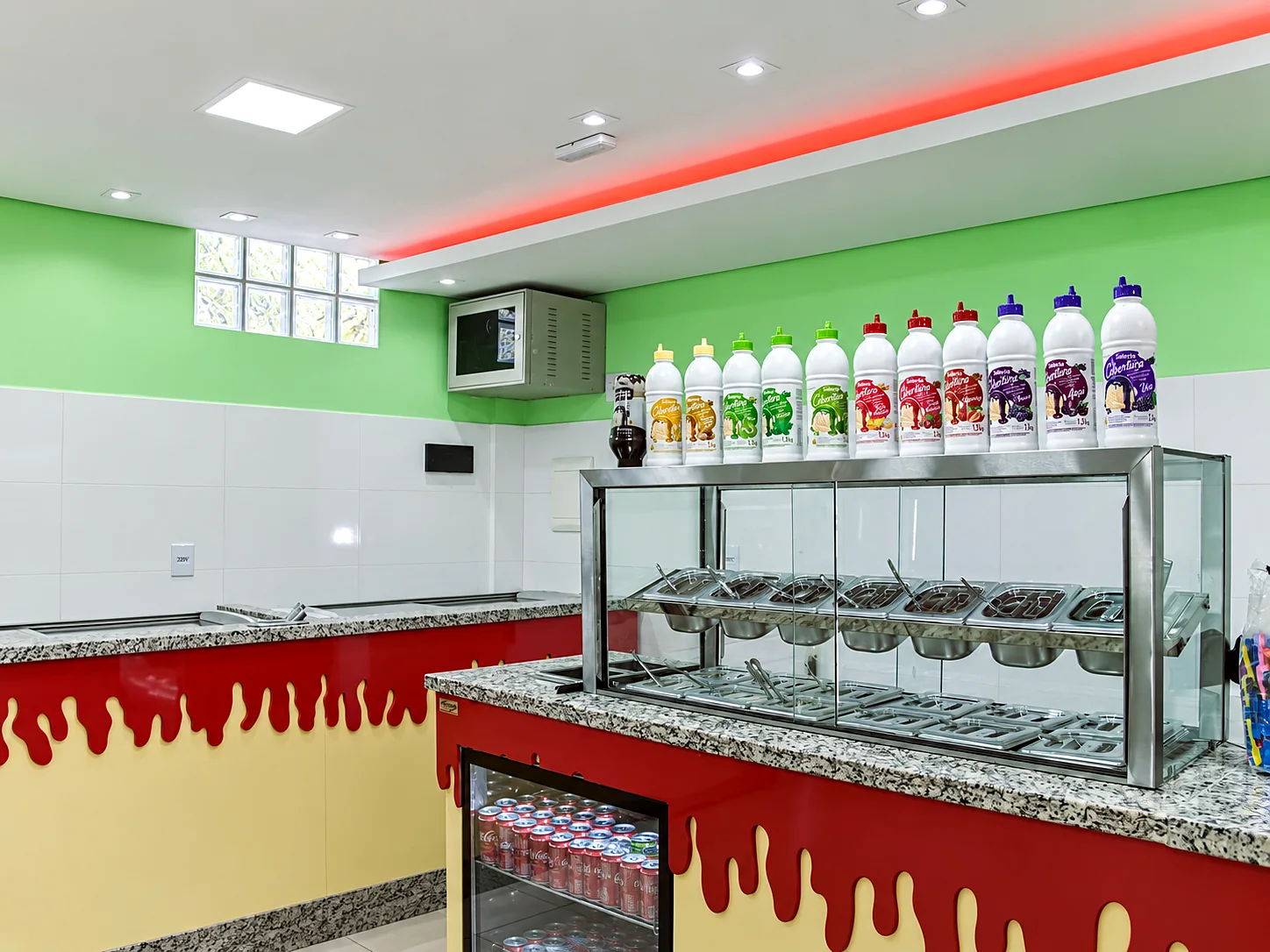 Balcão de açaí com vitrine de cubas em inox e coberturas expostas na prateleira superior