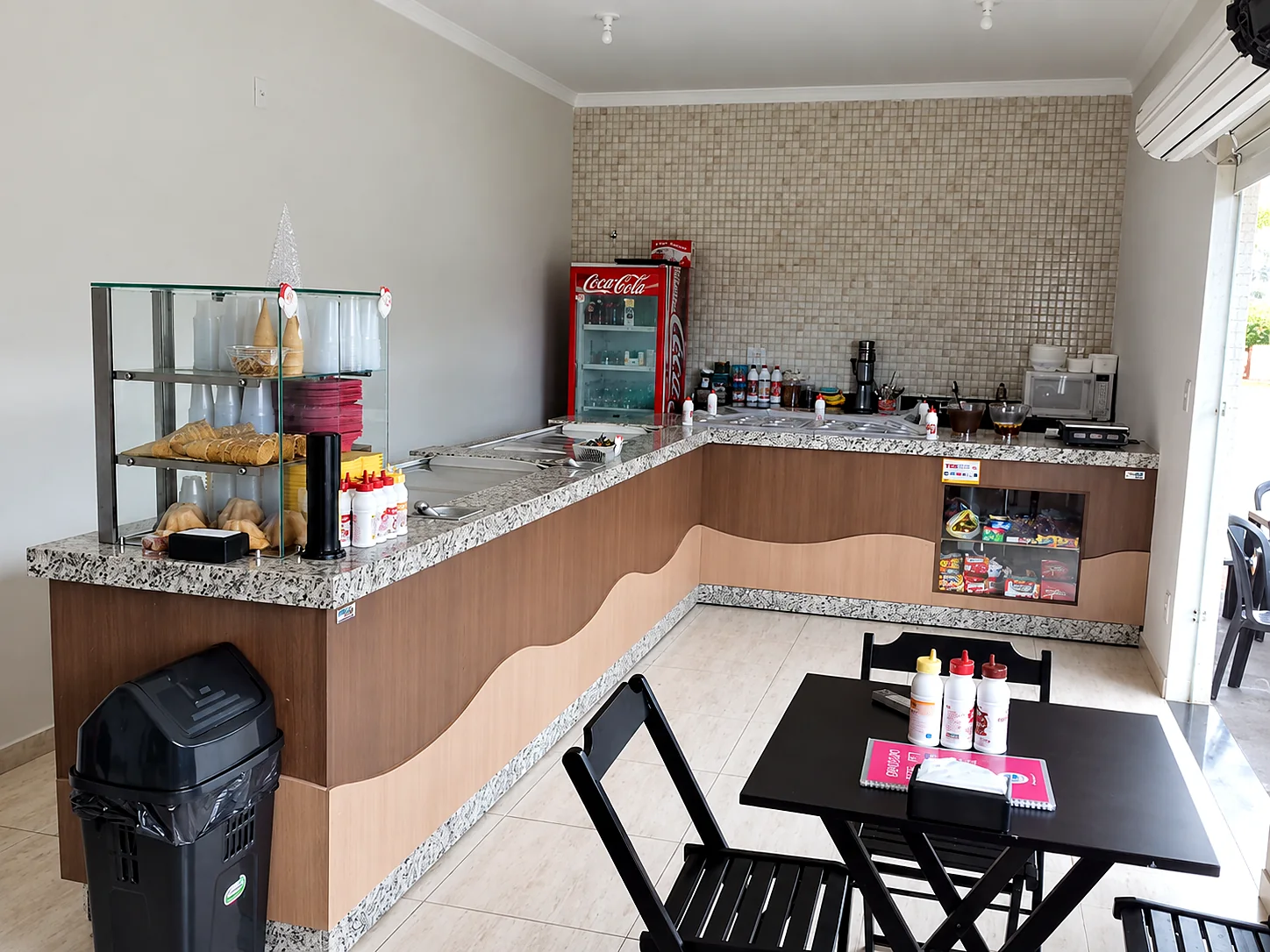 Balcão em L com tampo de granito, vitrine de casquinhas, cubas refrigeradas e expositor de doces
