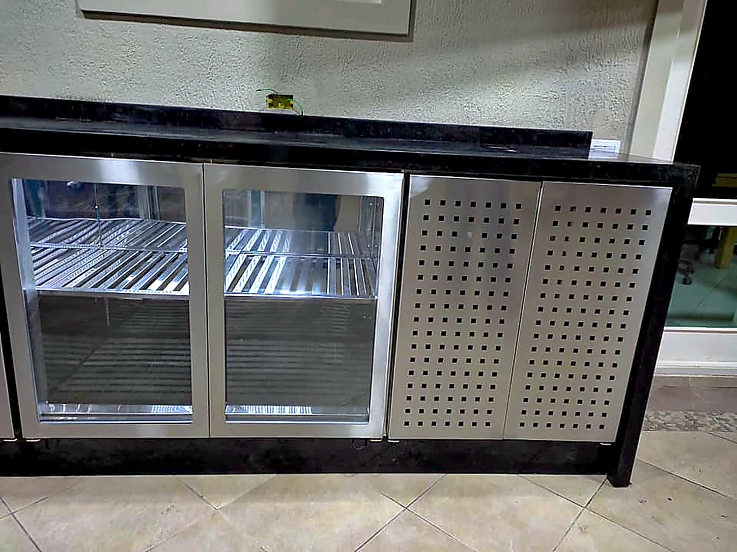 Detalhe das portas de vidro e do painel perfurado em inox do balcão refrigerado