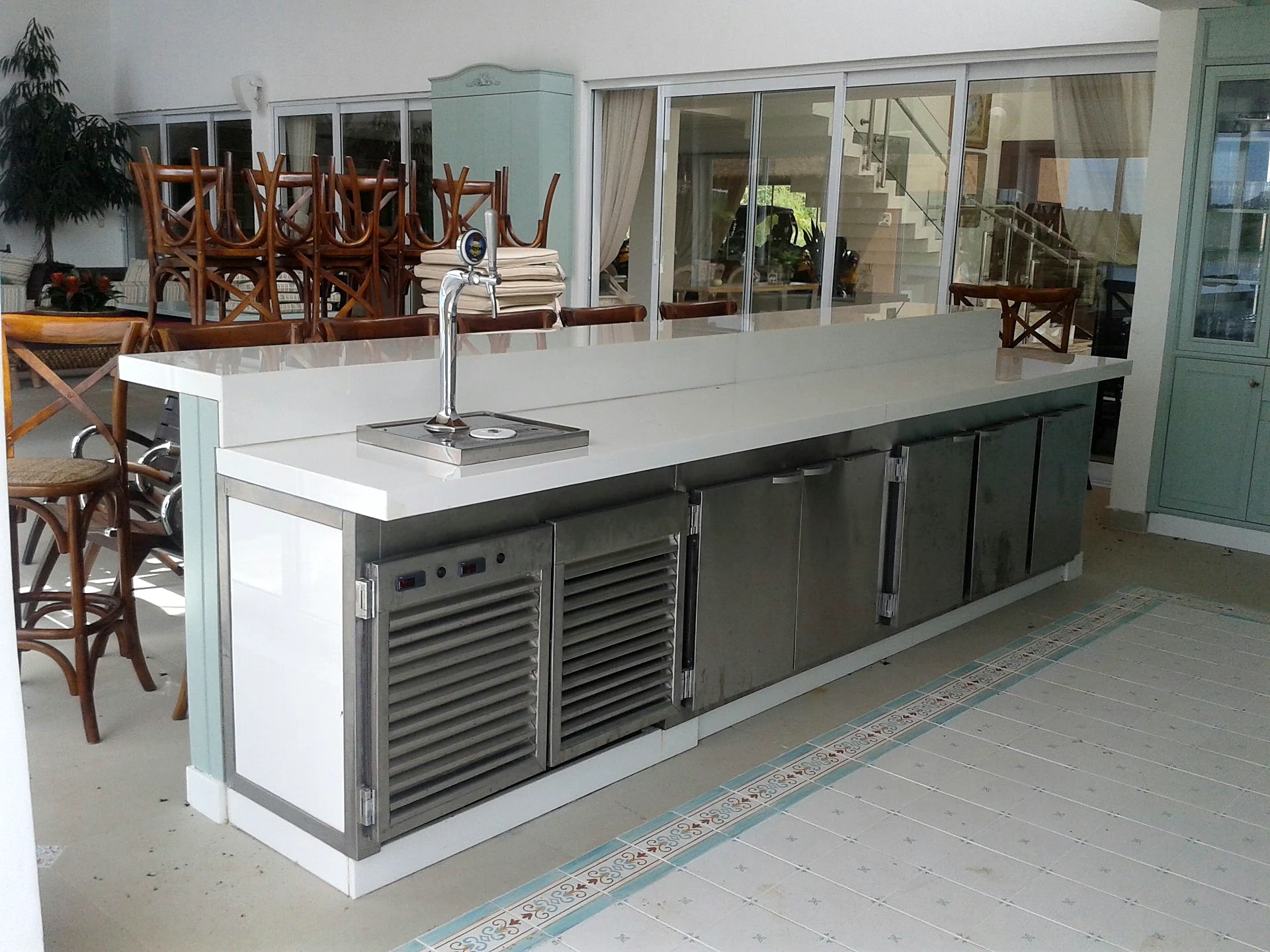 Balcão refrigerado longo com chopeira embutida, tampo claro, portas em inox e controladores de temperatura na frente