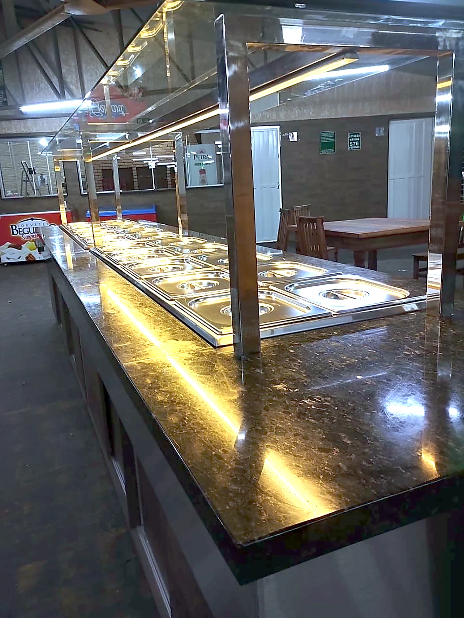 Linha de self service com cubas em inox, tampo de granito e iluminação embutida ao longo de todo o balcão