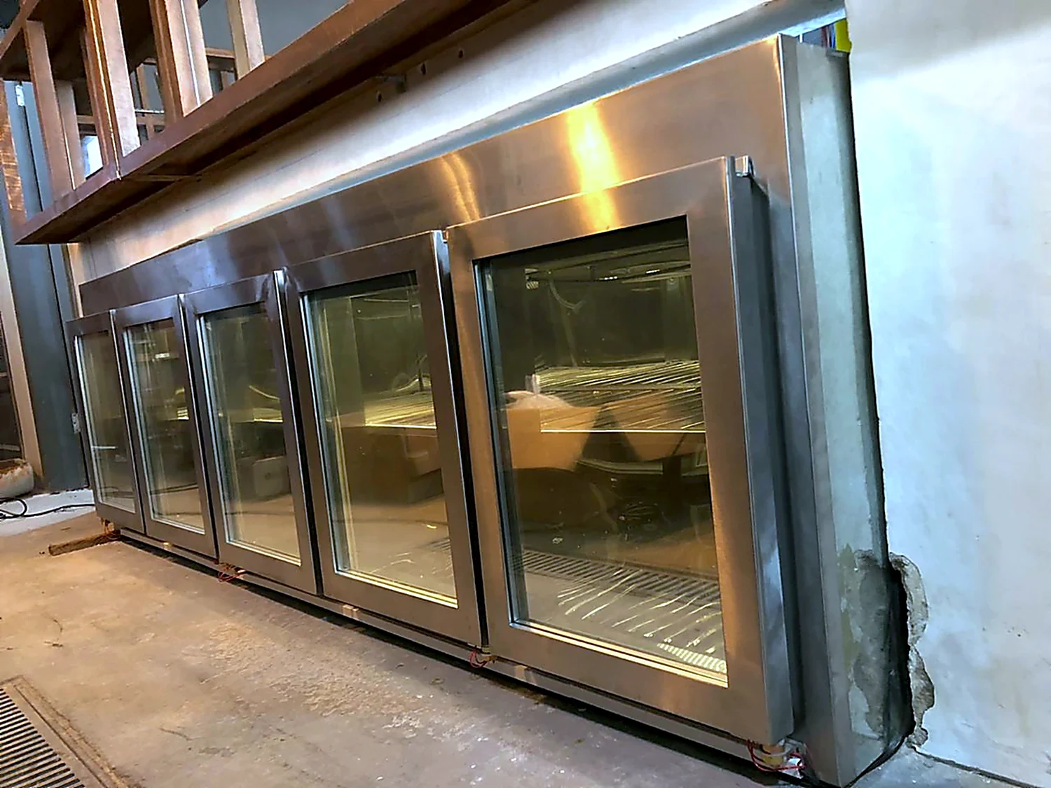 Balcão refrigerado em inox com portas de vidro durante a montagem